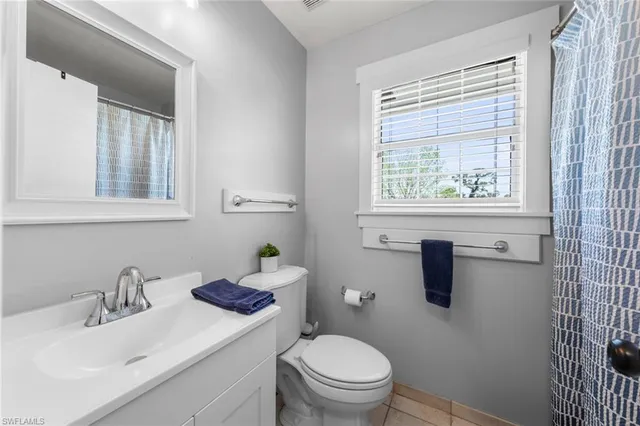 a bathroom with a granite countertop toilet a sink a mirror and a window