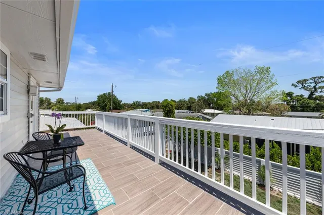 a view of a balcony with wooden chairs and floor to ceiling window