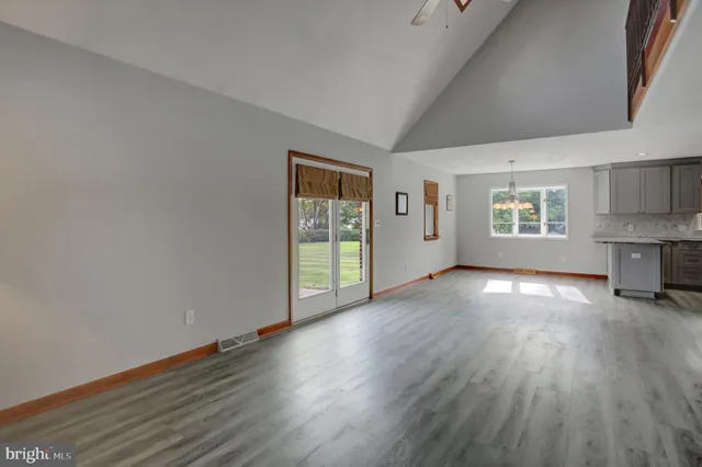 a kitchen with stainless steel appliances granite countertop a refrigerator a sink dishwasher a stove and white countertops with wooden floor