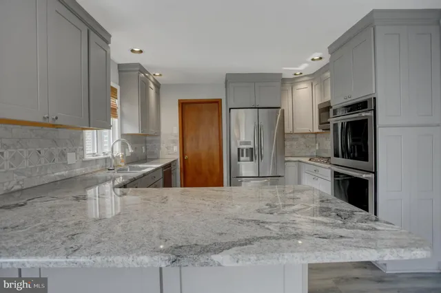 a kitchen with stainless steel appliances granite countertop a refrigerator a sink and wooden cabinets