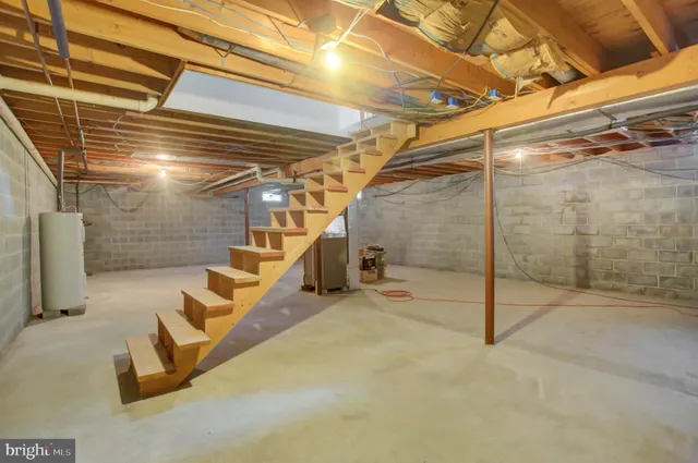 a house that is sitting in the grass with large trees and plants