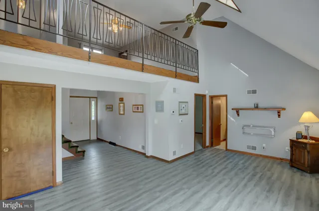 a view of an empty room with wooden floor and a kitchen