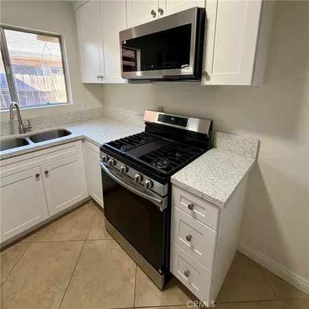 a kitchen with white cabinets and black appliances