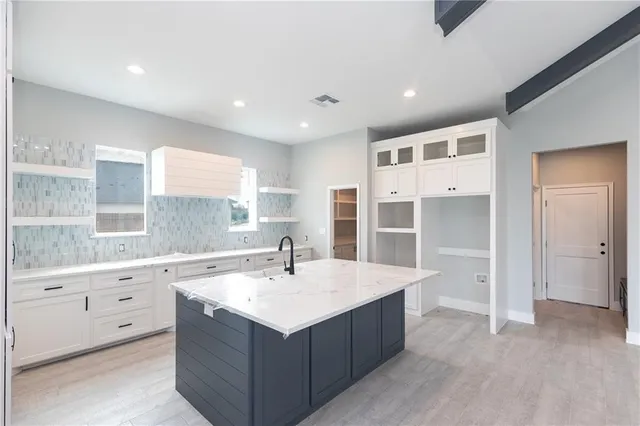 a large white kitchen with a sink a counter space and stainless steel appliances