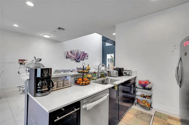 a kitchen with a sink dishwasher and a refrigerator with white cabinets