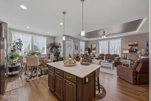 a view of a dining room and livingroom with furniture wooden floor a rug a flat screen tv a rug a painting and a chandelier