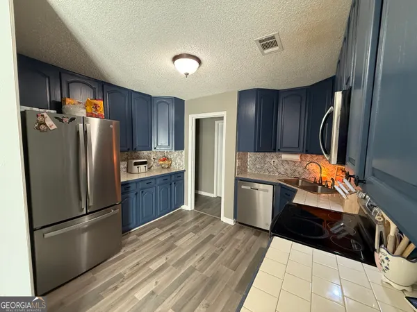 a kitchen with stainless steel appliances a refrigerator sink and wooden cabinets