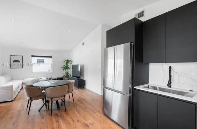 a kitchen with stainless steel appliances a refrigerator a sink a stove a dining table and chairs