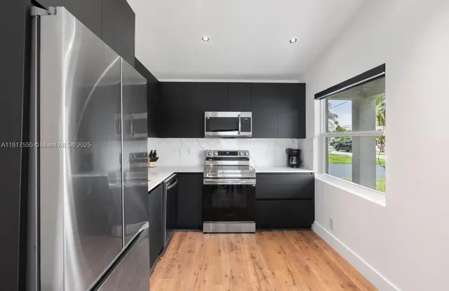 a kitchen with stainless steel appliances granite countertop a refrigerator and a stove top oven