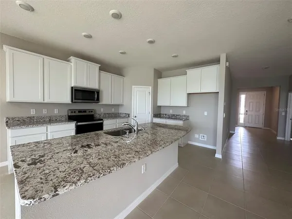 a kitchen with granite countertop a sink a counter top space appliances and cabinets