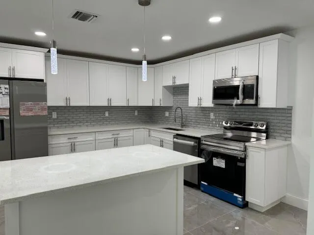 a kitchen with stainless steel appliances a stove a sink a microwave and cabinets
