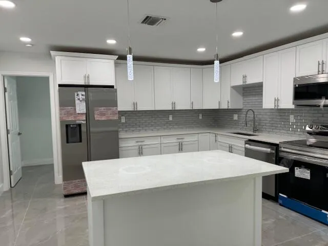 a kitchen with kitchen island a sink stainless steel appliances and cabinets