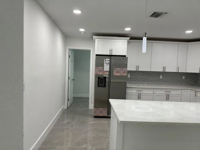a kitchen with kitchen island a refrigerator and a sink