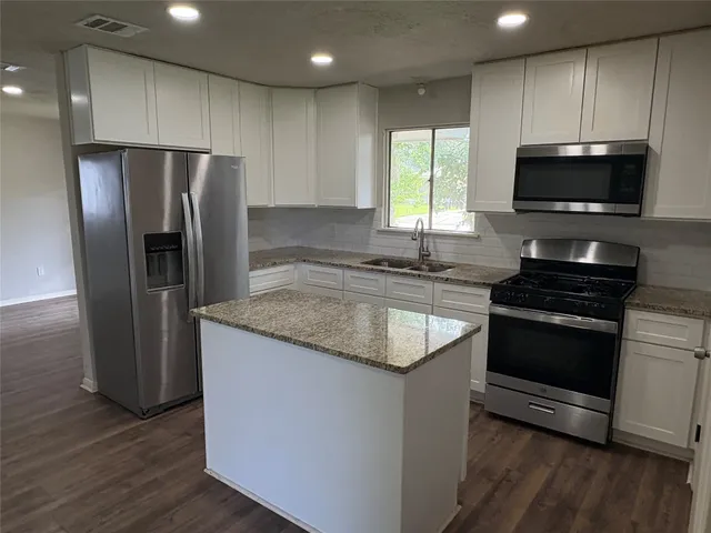 a kitchen with stainless steel appliances granite countertop a sink stove and refrigerator