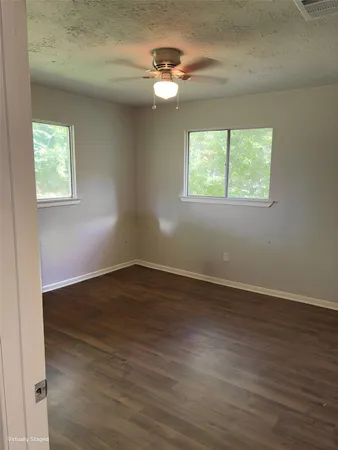 an empty room with wooden floor chandelier fan and windows