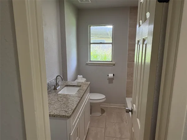 a bathroom with a granite countertop sink a toilet and a mirror