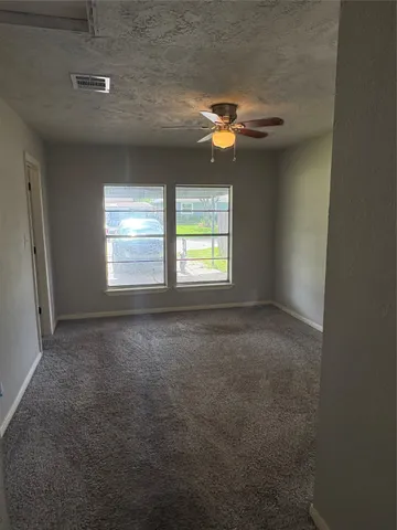 an empty room with windows and chandelier fan