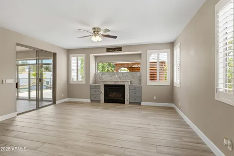 an empty room with windows fireplace and a ceiling fan
