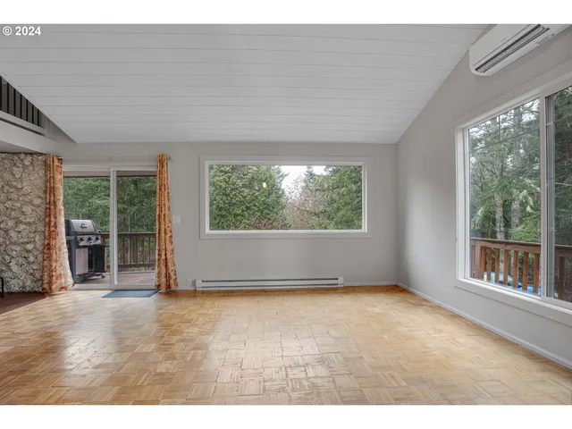 a view of an empty room with wooden floor and windows