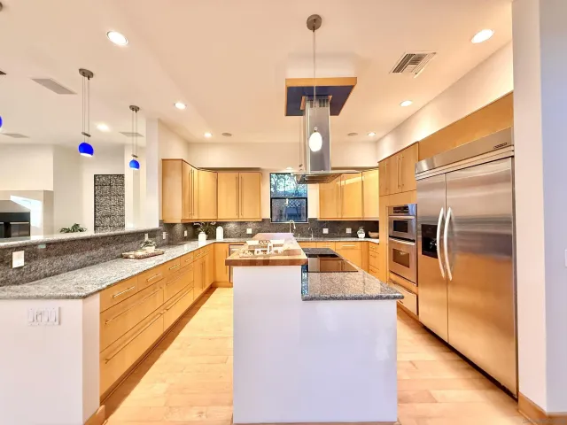 a kitchen with stainless steel appliances granite countertop a sink a stove and a refrigerator