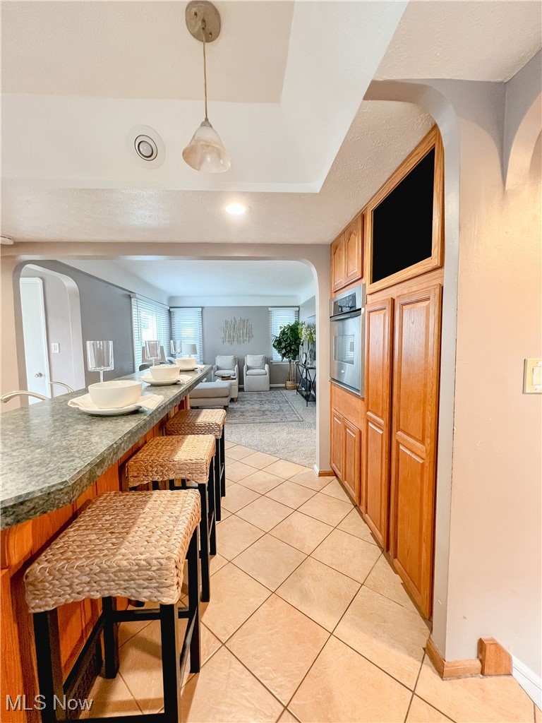 6403 Kenneth Avenue Parma, OH 44129 - Photo 20 of 20 Kitchen with arched walkways, pendant lighting, a kitchen breakfast bar, light tile patterned floors, and open floor plan