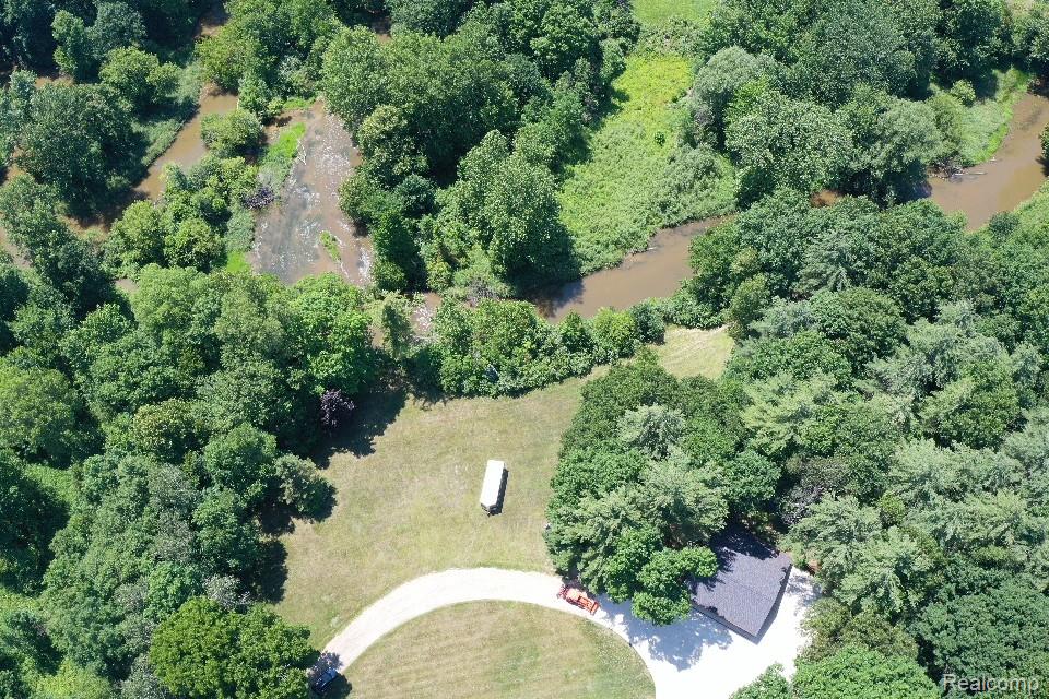 3656 Stanley Road Columbiaville, MI 48421 - Photo 51 of 65 Extensive natural landscape featuring mature trees, a winding waterway, and a partially visible structure with a dark roof