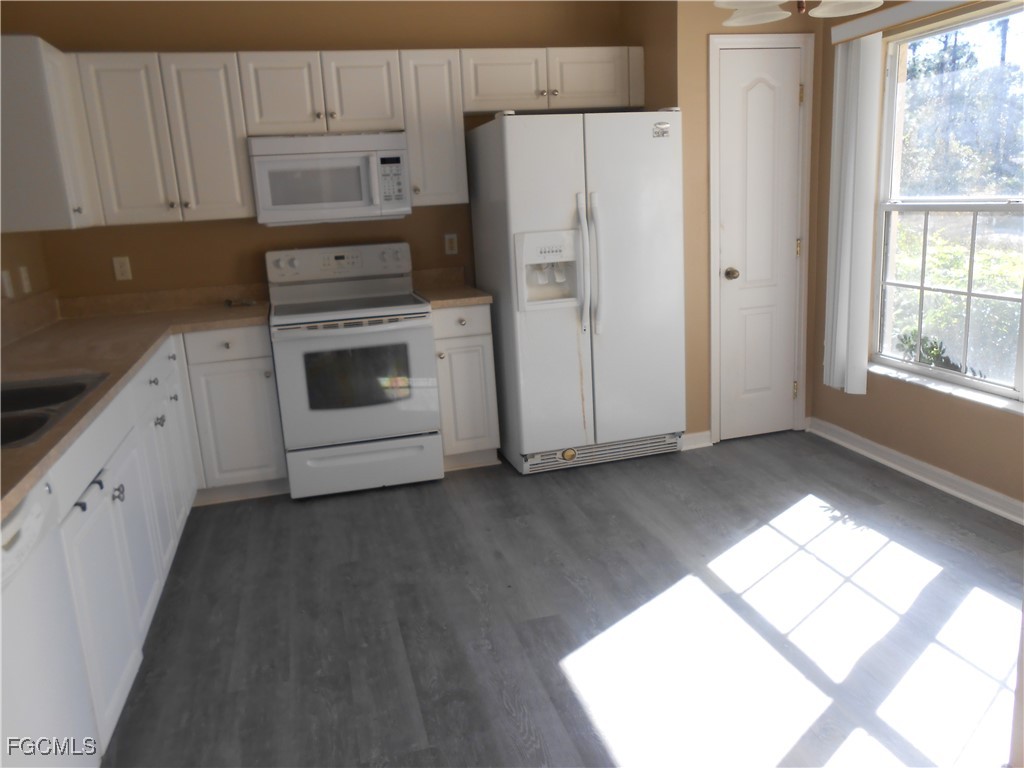 3208 71st Street West Lehigh Acres, FL 33971 - Photo 5 of 24 a kitchen with a white cabinets and white appliances