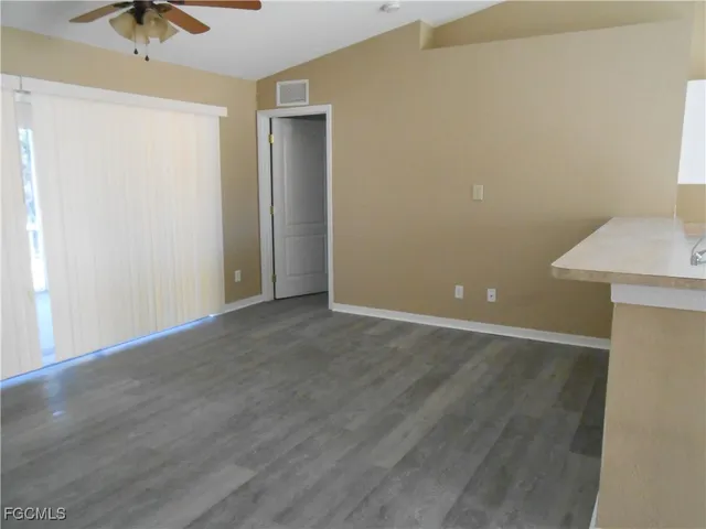 an empty room with a ceiling fan and carpet