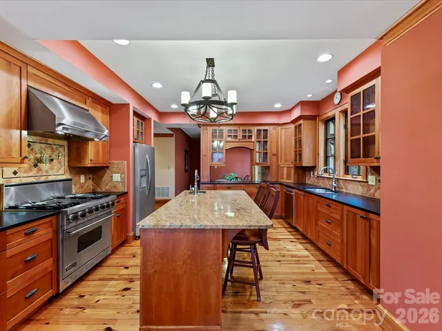 a large kitchen with stainless steel appliances kitchen island granite countertop a stove a sink dishwasher and cabinets with wooden floor