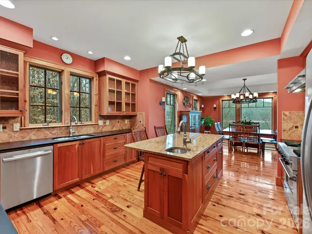 a kitchen with stainless steel appliances granite countertop a stove top oven a dining table and chairs with wooden floor