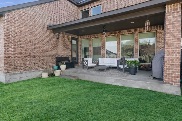 a view of a patio with table and chairs potted plants and floor to ceiling window