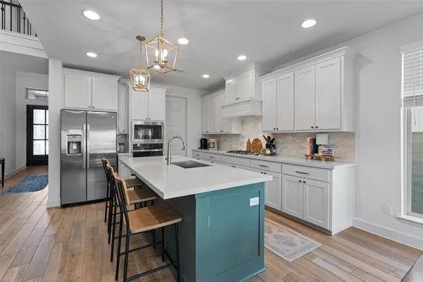 a kitchen with stainless steel appliances kitchen island a table chairs refrigerator sink and cabinets