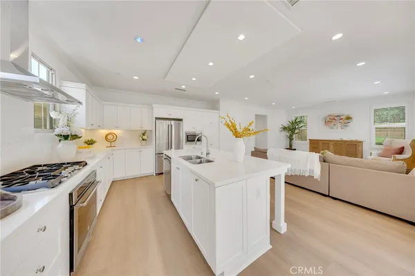 a large white kitchen with cabinets a sink a window and stainless steel appliances