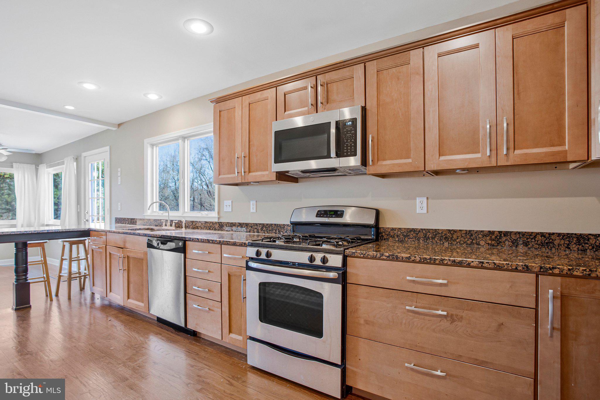 5967 Brooks Woods Road Lothian, MD 20711 - Photo 5 of 15 a kitchen with granite countertop wooden cabinets stainless steel appliances and a window