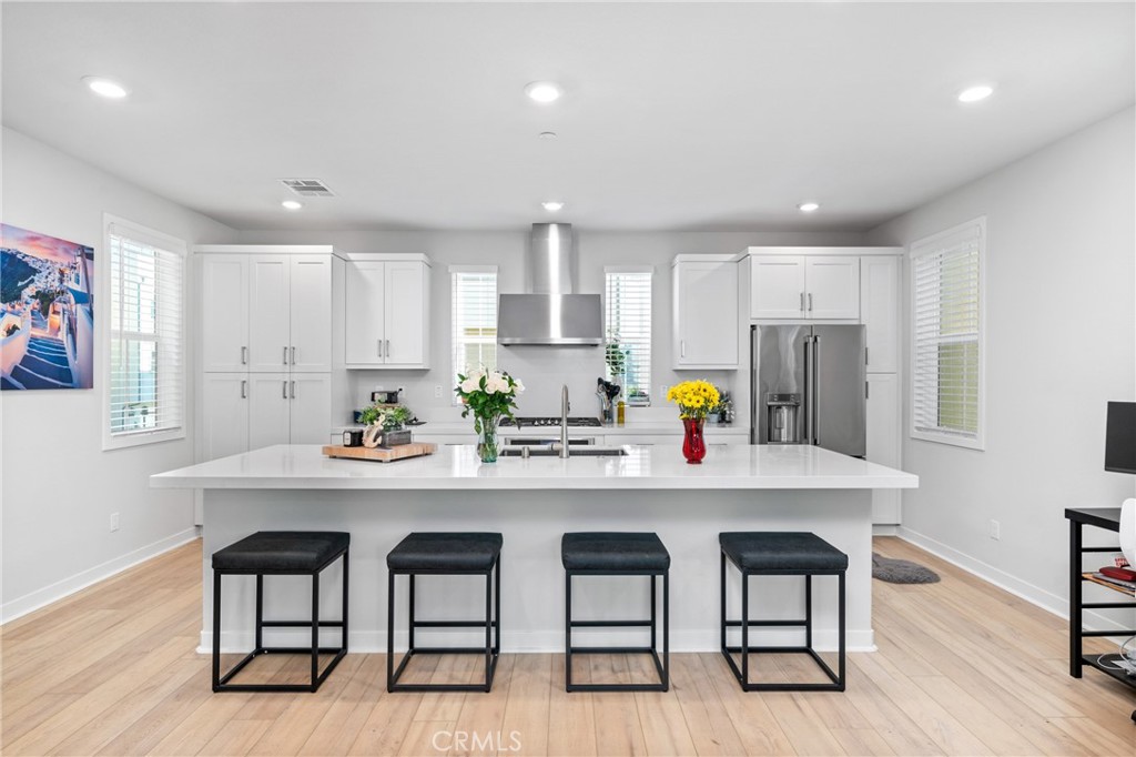 a kitchen with stainless steel appliances a dining table chairs and wooden floor
