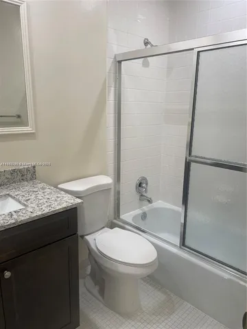 a bathroom with a granite countertop bathtub shower sink vanity and toilet