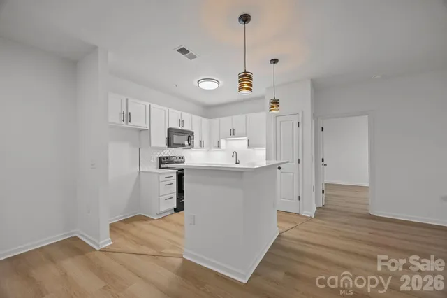 a kitchen with stainless steel appliances granite countertop a sink a stove a refrigerator and white cabinets