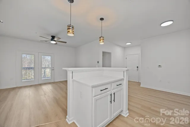 a view of an empty room with wooden floor and a ceiling fan