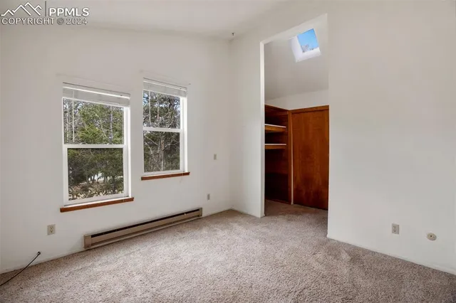 an empty room with a chandelier fan and windows