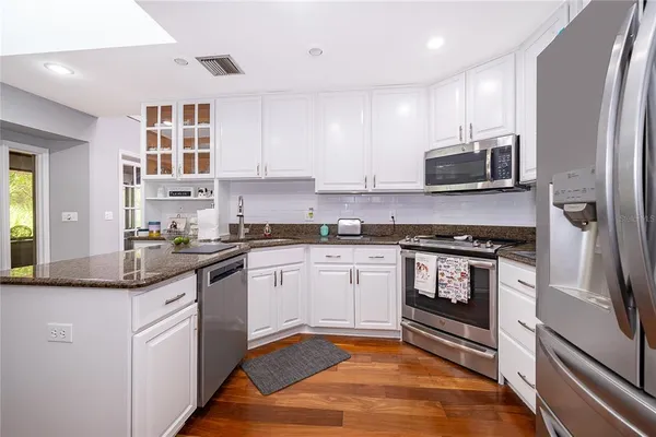 a kitchen with stainless steel appliances granite countertop a refrigerator a stove top oven a sink and dishwasher