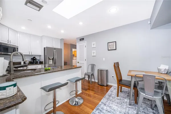 a kitchen with stainless steel appliances granite countertop a dining table chairs and a refrigerator