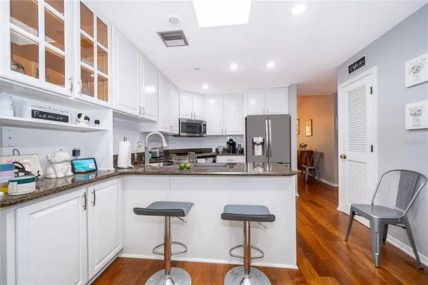 a kitchen with stainless steel appliances a sink a stove a refrigerator cabinets and dining table