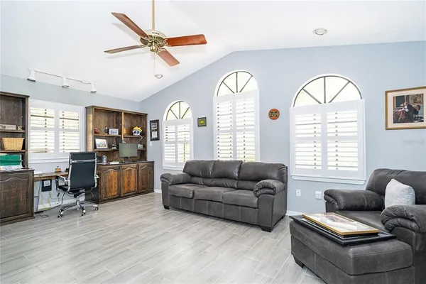 a living room with furniture two window and a flat screen tv