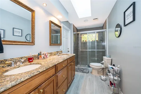a bathroom with a granite countertop sink mirror vanity and toilet