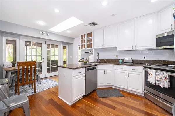 a kitchen with granite countertop appliances cabinets and a dining table with wooden floor