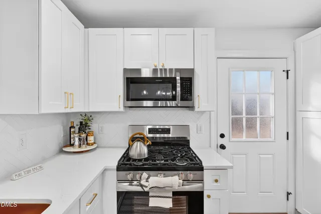 a kitchen with white cabinets and window