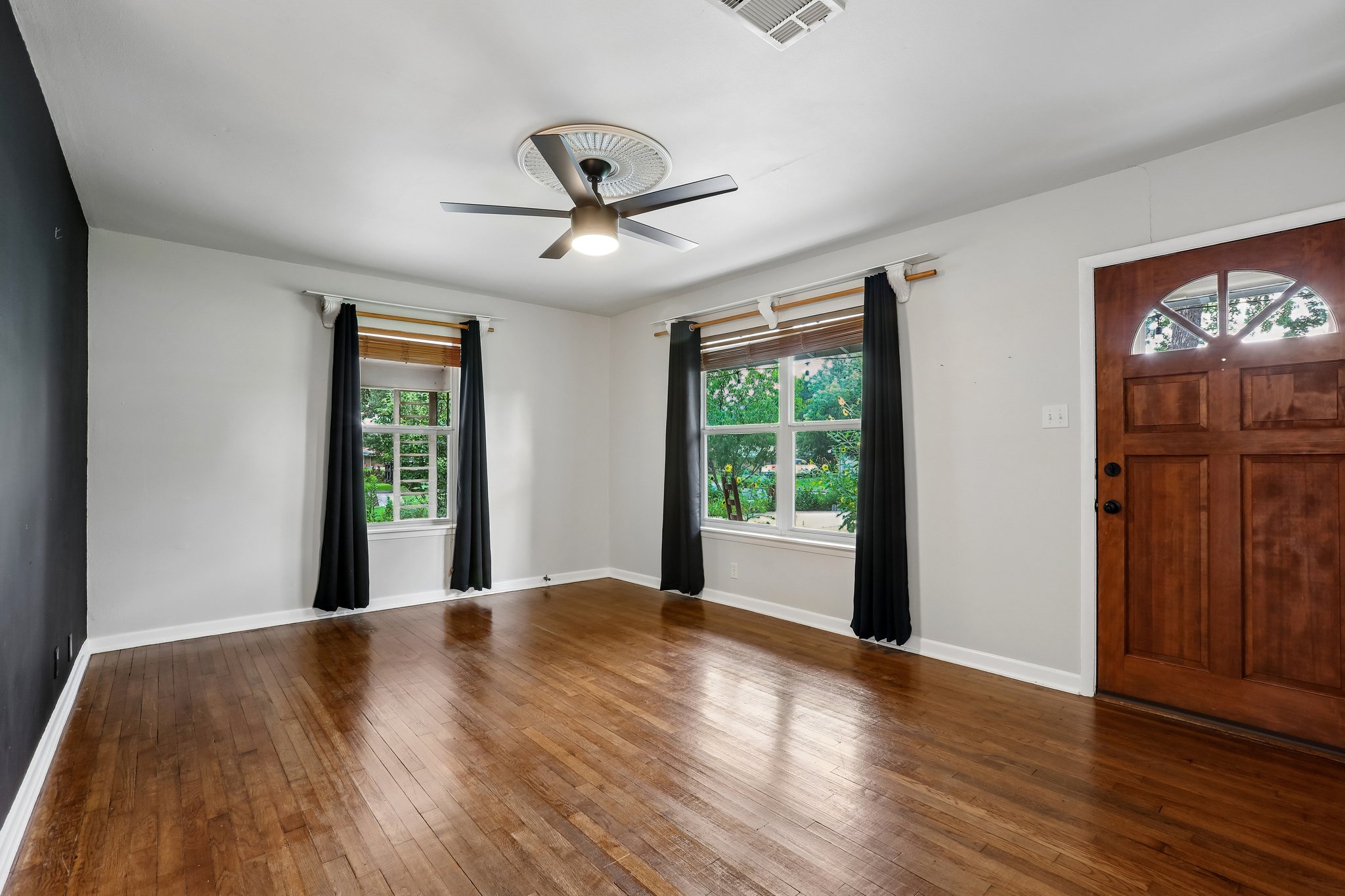1114 West 2nd Street Elgin, TX 78621 - Photo 5 of 31 Natural light floods through multiple windows, illuminating the beautiful hardwood flooring of this inviting space.