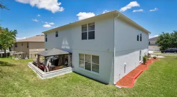 a view of house and yard with swimming pool and sitting area