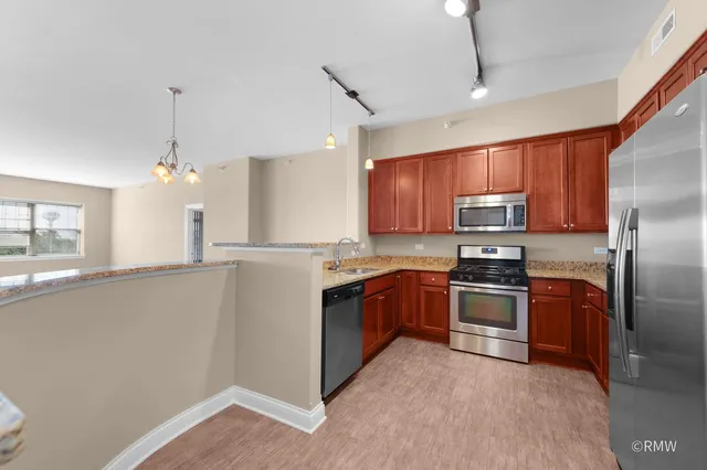 a kitchen with stainless steel appliances granite countertop a refrigerator a stove top oven a sink and dishwasher