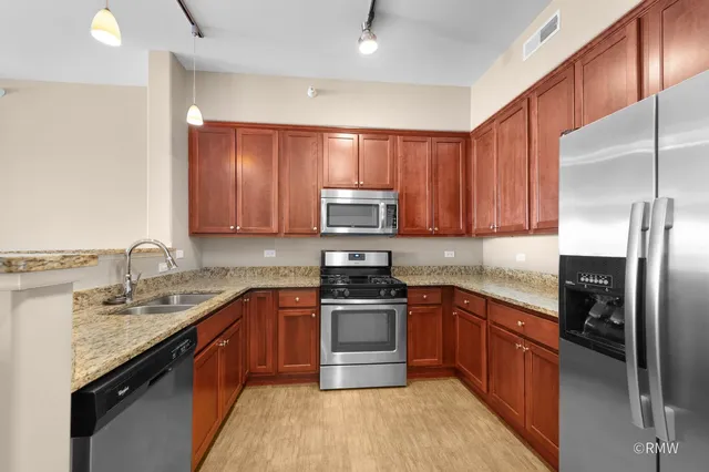 a kitchen with stainless steel appliances granite countertop a sink stove microwave and refrigerator